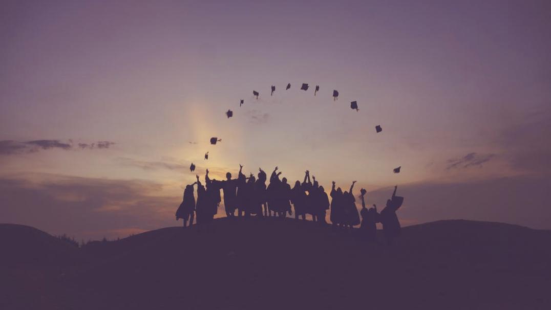 High school graduates crowded on the edge of a cliff, tossing their caps into the air, welcoming a summer to remember