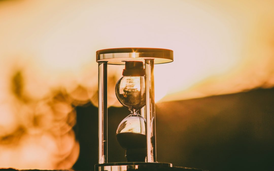 An hourglass set against a beautiful golden hour sunset counting down the time to application deadlines.